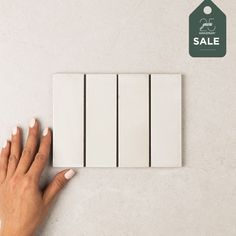 a woman's hand is touching the white tiles