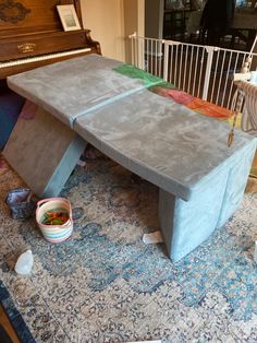 a bench made out of concrete sitting on top of a blue rug next to a piano