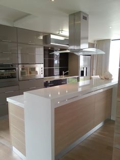 a modern kitchen with stainless steel appliances and white counter tops, along with wood flooring