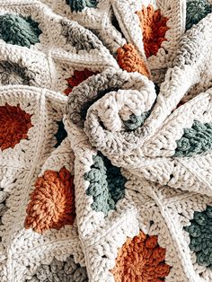 a crocheted blanket with orange and green leaves on the edges is shown in close up