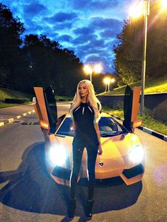 a woman standing in front of a yellow sports car with its doors open at night