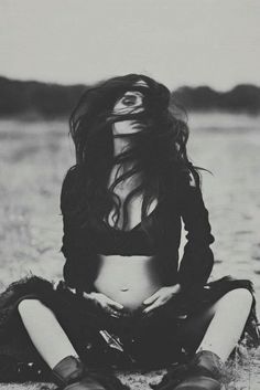 a black and white photo of a woman sitting on the ground with her eyes closed