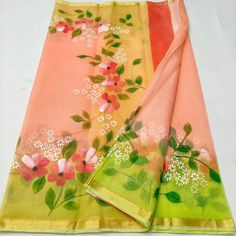 an orange and pink sari with flowers on the border, sitting on a white surface