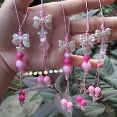 pink and white beaded necklaces being held in someone's hand with green leaves behind them