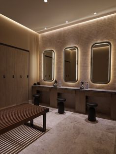 a bathroom with three sinks, mirrors and stools on the wall next to each other