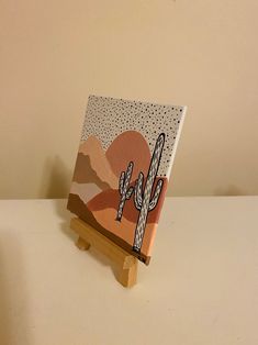 a small wooden easel with a cactus painting on it