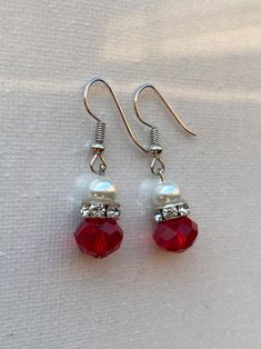 pair of red crystal and pearl earrings on white fabric background with clipping for earwires