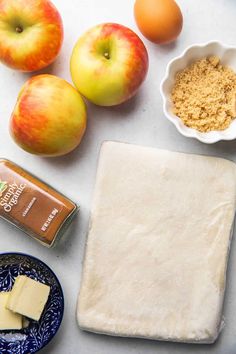 ingredients to make an apple pie laid out on a white counter top, including apples and butter