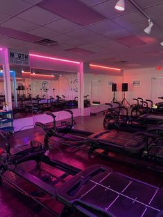 an empty gym with many exercise machines and lights on the wall behind them in front of mirrors