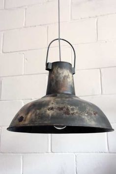 an old metal light hanging from a brick wall with white bricks in the back ground