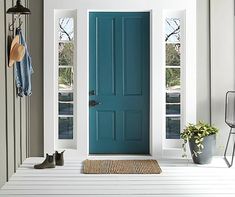 a blue front door with two windows and a rug on the floor next to it