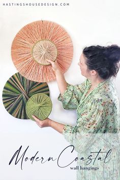 a woman is holding three fan shaped artwork on the wall with her hands and looking at it