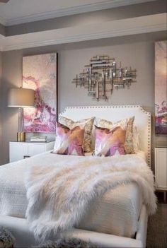 a white bed topped with lots of pillows next to a wall mounted art piece in a bedroom