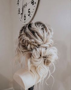 a woman's hair is braided into a bun in front of a clock