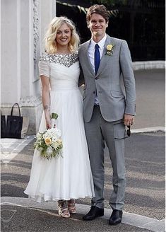 a man and woman standing next to each other in front of a building with flags