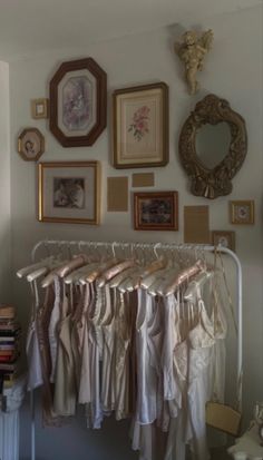 there are many pictures on the wall and clothes hanging up in front of them,