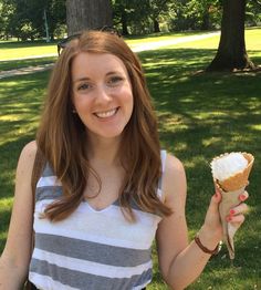 a young woman holding an ice cream cone in her hand and smiling at the camera