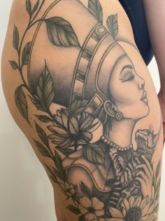 the back of a woman's thigh with tattoos on her body and flowers around it