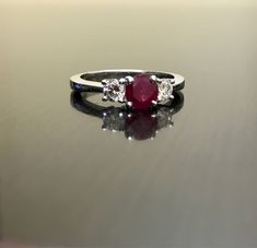 DeKara Designs Collection Classic/Modern Three Stone Diamond Past Present and Future Engagement Ring. Metal- 90% Platinum, 10% Iridium Stones- 1 Round Natural Pigeon Blood Ruby 0.71 Carats, 2 Round Diamonds, G color VS1 clarity, .44 carats. Art Deco Inspired Beautiful Pigeon Blood Red Ruby Three Stone Diamond Engagement Ring Made in Platinum. There is a vibrant and fiery round ruby that is professionally set in between four prongs. There is one round fiery diamond on each side of the the ruby th Formal White Gold Ruby Ring With Three Stones, Gia Certified White Gold Ruby Ring, Classic Three Stone Round Ruby Ring, Classic Gia Certified Round Ruby Ring, Wedding Ruby Ring With Platinum Accent Stones, Ruby Ring With Accent Stones In Platinum, White Gold Three Stone Proposal Rings, White Gold Three Stone Ring For Proposal, Classic Silver Gia Certified Ruby Ring