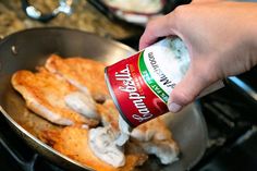 a person is adding seasoning to chicken in a skillet