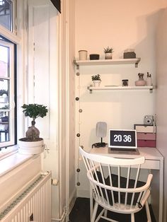 a laptop computer sitting on top of a white desk next to a potted plant