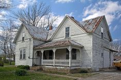 an old white house sitting on the side of a road