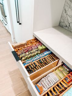 an open drawer in a kitchen filled with snacks and drinks on top of it's drawers