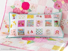 a pink and white quilted pillow on top of a bed next to a wall