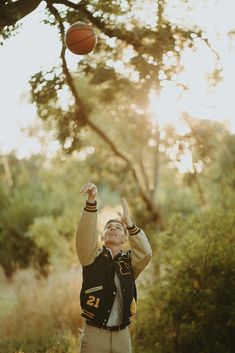 a young boy is reaching up to catch a basketball in the air with his right hand