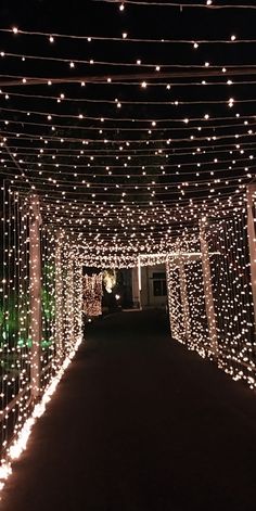 the walkway is covered in white lights and string lights that are hanging from the ceiling