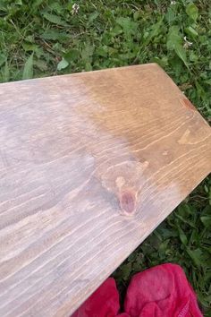 a piece of wood sitting on top of grass next to a pair of red shoes