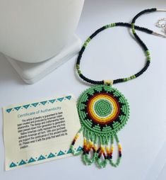 a beaded necklace with a card on it next to some beads and a keychain