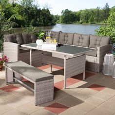 an outdoor table and bench set on a patio with water in the backround