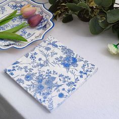 blue and white plates sitting on top of a table next to tulips in vases