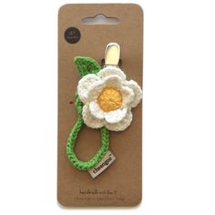 a white flower on a green cord with a tag attached to the back of it