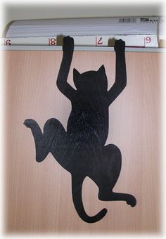 a black cat is hanging on the wall