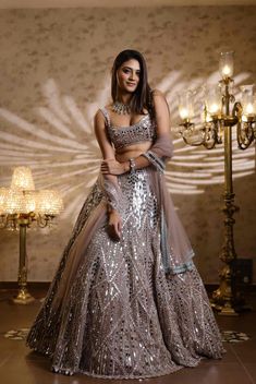 This champagne lehenga set features intricate embroidery in mirror, thread, sequin and crystals. Paired with a strappy embellished blouse and matching embroidered dupatta.From Isa by Dolly Wahal's Fiori collection.DELIVERY TIMEPlease allow 8-12 weeks for your outfit to arrive.FABRIC DETAILSNetProfessional cleaning only. Glamorous Festive Choli With Mirror Work, Glamorous Choli With Mirror Work For Reception, Festive Silver Hand Embellished Sharara, Glamorous Lehenga With Sequins In Saree Style, Glamorous Choli With Mirror Work For Diwali, Glamorous Choli With Zari Work For Diwali, Glamorous Festive Lehenga For Reception, Festive Glamorous Choli With Zari Work, Glamorous Designer Wear Hand Embellished Sharara