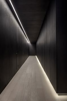 an empty hallway with wooden walls and lights on the ceiling is lit by recessed lighting