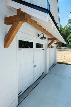 a row of white garage doors on the side of a house with wood trimming