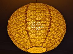 a yellow lamp hanging from the ceiling in a dark room with dim lighting on it