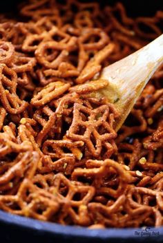 a wooden spoon is stirring some food in a skillet filled with pretzels