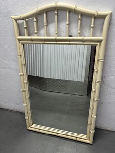 a white bamboo mirror sitting on top of a floor