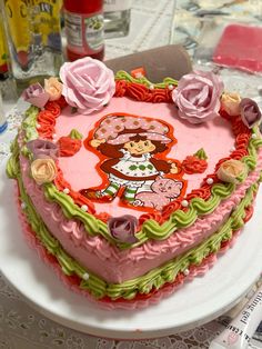 a heart shaped cake decorated with flowers and an image of a cartoon character on it