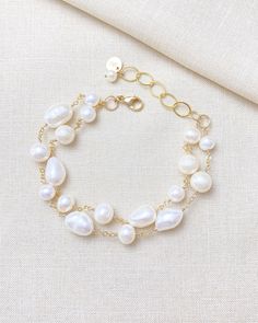 Make a classic and elegant statement with this multi-layered mixed pearl bracelet. Two handcrafted strands of differently shaped and sized pearls create a versatile accessory suitable for weddings, brunches, work, and more. The lobster clasp and extender ensure a secure and adjustable fit. Length: 7.5 inches plus 1.5-inch extender Materials: gold fill, cultured freshwater pearls GIFTING ~ Jewelry gift box included. ~ I am happy to ship directly to the recipient.  Enter their address during check Baroque Pearl Bracelets For Wedding, Baroque Pearl Wedding Bracelets, Wedding Baroque Pearl Chain Bracelet, Elegant Baroque Pearl Bracelet For Wedding, Elegant Baroque Pearl Bracelet, Multi-strand Pearl Bracelets As Gift, Elegant Baroque Pearl Beaded Bracelets For Wedding, Pearl Beaded Bracelets With Pearl Charm For Wedding, Elegant Pearl Chain Bracelet For Wedding