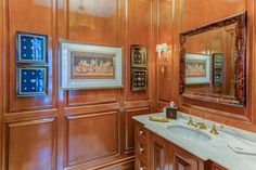 a bathroom with wood paneling and framed pictures on the wall, along with two sinks