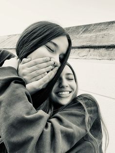 two young women are hugging each other outside