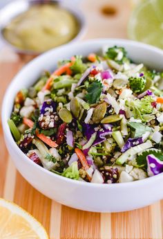 a white bowl filled with salad next to sliced oranges and lime wedged on the side