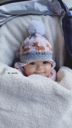 a baby in a stroller with a blanket and hat on it's head