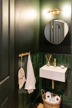 a bathroom with green tile and white towels on the rack next to the sink in front of the mirror