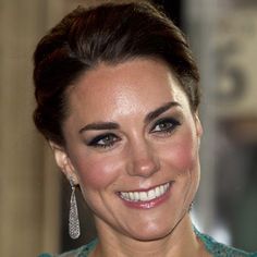 a woman in a green dress smiling at the camera with big earrings on her head